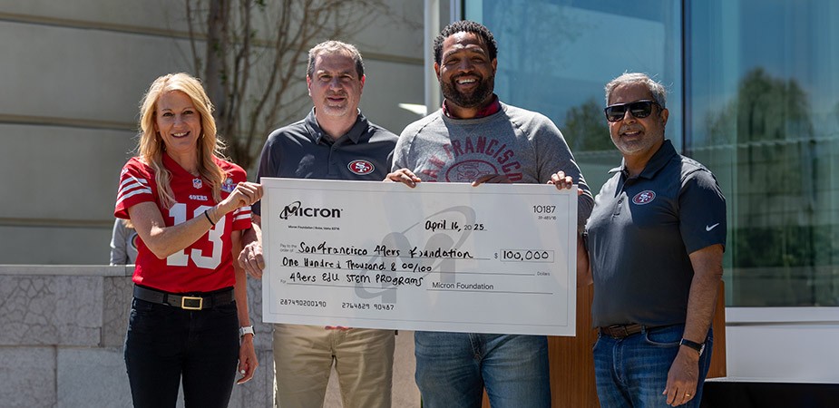group of 4 people holding a cheque of 100,000 dollars with Micron Chairman, President and CEO Sanjay Mehrotra standing on exterme right
