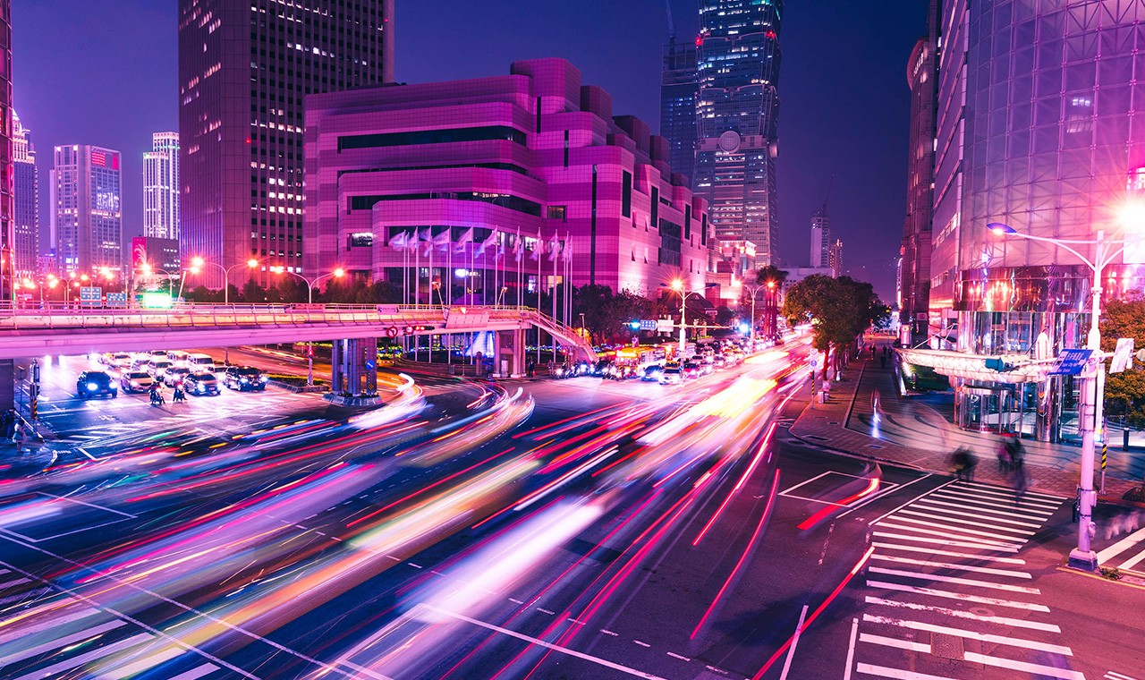 night view of lighted skyscrapers with beams of car lights